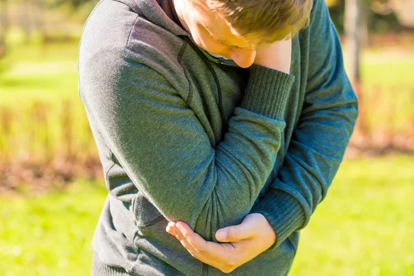 Jeune homme attrapé la main mal au coude — Photo