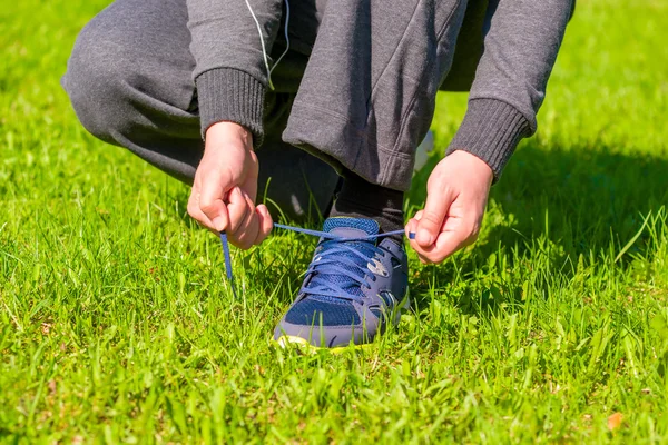 Tangan manusia mengikat tali sepatu dari sepatu olahraga. — Stok Foto