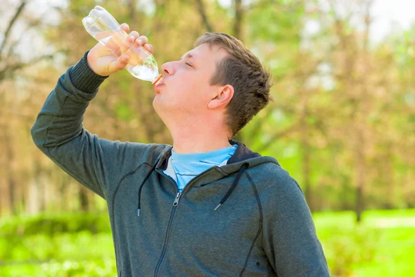 Horizontale portret van een man drinkwater uit een klein flesje — Stockfoto