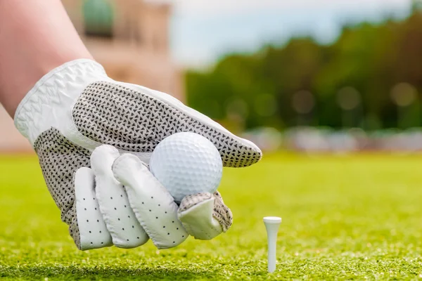 Tee yakınındaki bir golf topu tutan closeup el — Stok fotoğraf