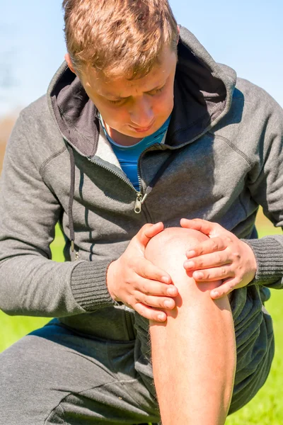 Athlete inspects diseased knee while jogging — Stock Photo, Image