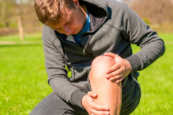 Portrait of a man inspecting his injured leg — Stock Photo, Image