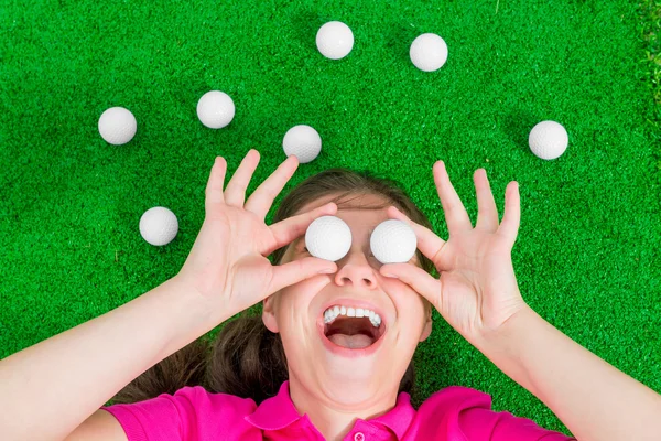 Retrato engraçado de uma menina com bolas de golfe — Fotografia de Stock