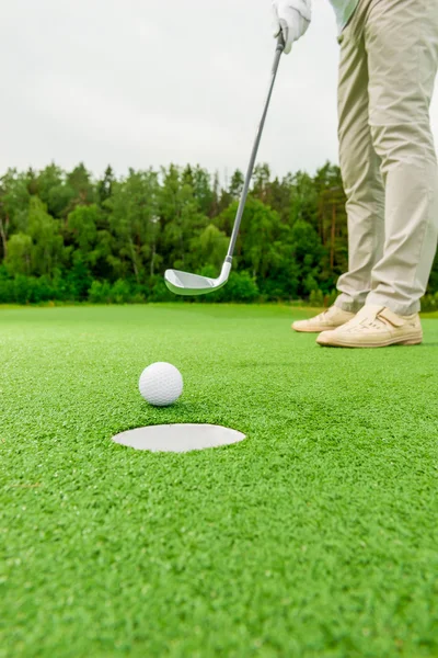 Lyuk, és a labda közelkép, életlen golfozó — Stock Fotó