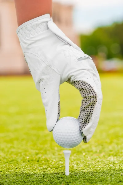 Fehér kesztyűt kezét helyezi a golf labda egy póló — Stock Fotó