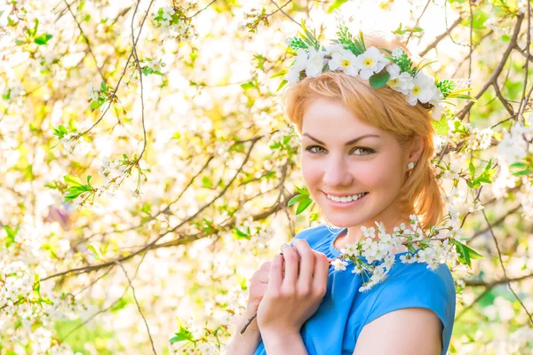 Chica sonriendo en el fondo de la cereza en flor en el parque —  Fotos de Stock