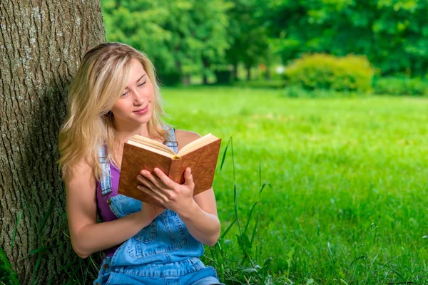 Güzel genç kız öğrenci parkta iyi bir kitap ile — Stok fotoğraf