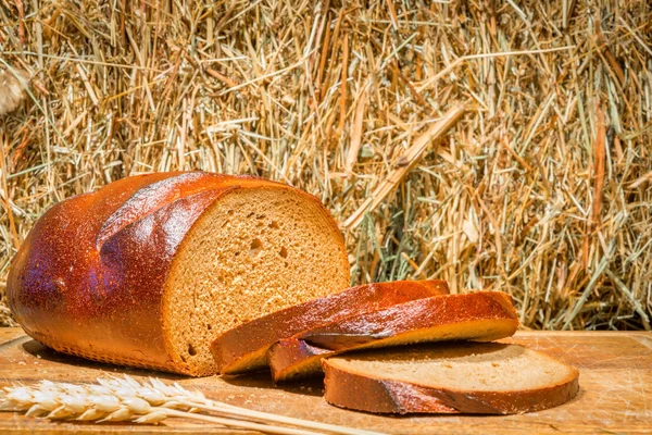 Slices of freshly baked rye bread on the background of haystack — Stock Photo, Image