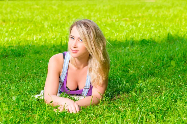 Привлекательная девушка отдыхает на зеленой траве в парке — стоковое фото