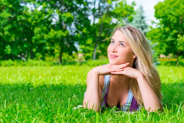 Dreamy girl resting on the green grass in the park — Stock Photo, Image