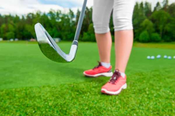 Dámské nohy a golf putter na zelené trávě — Stock fotografie