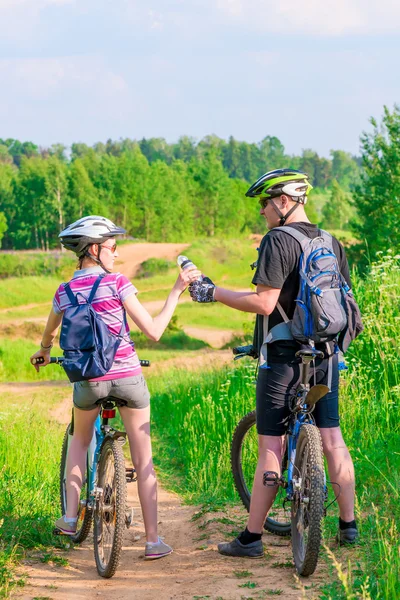 Man gives a girl to drink water on a bicycle — Stock Photo, Image