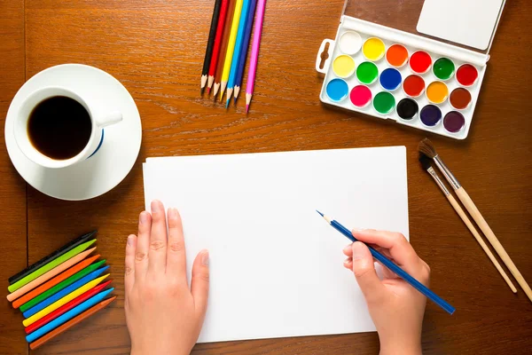 Kvinnornas händer med en blå penna på bordet ritning — Stockfoto