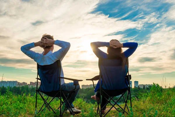 Couple sitting in chairs and admire the sunrise over the city — Stock Photo, Image