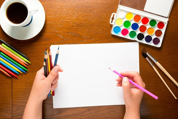 Vista superior de una mano con lápiz y hoja de papel en blanco — Foto de Stock