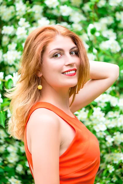 Portret van een jonge vrouw op een achtergrond van jasmijn — Stockfoto