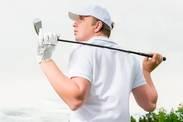 Golfista em um boné contra o céu com um taco de golfe — Fotografia de Stock