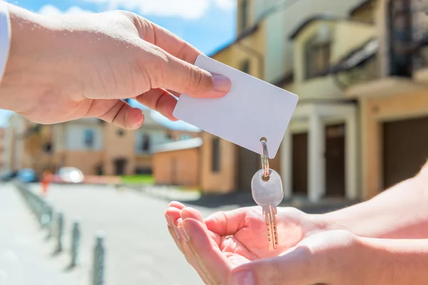 Key of apartment and a card for an inscription in the hands of p — Stock Photo, Image