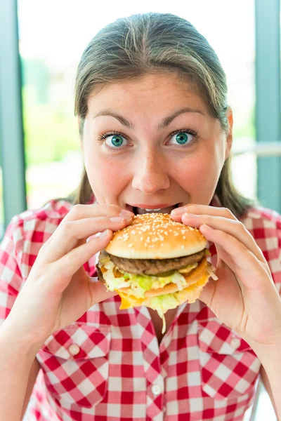 Éhes lány kézen egy hamburger — Stock Fotó