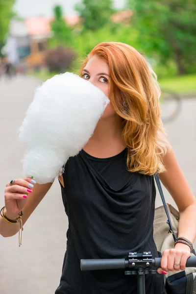 Chica 30 años caminando en el parque y comer algodón de azúcar — Foto de Stock