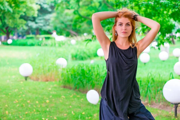 Bella donna in un parco in abito nero — Foto Stock