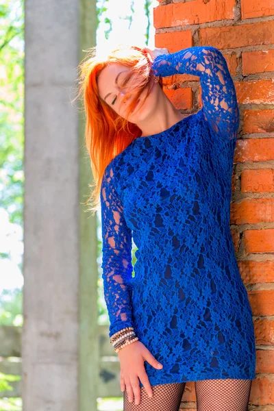 Menina com cabelo vermelho posando perto da parede de tijolo — Fotografia de Stock