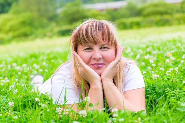 美丽的成熟女人，躺在草地上，微笑 — 图库照片