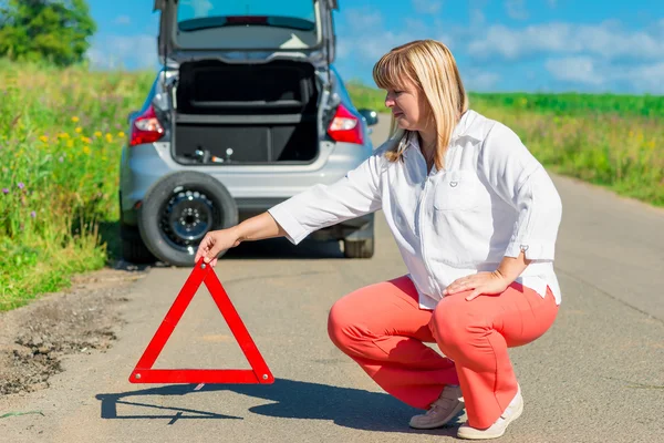 Feminino 50 anos, define no triângulo de aviso de estrada — Fotografia de Stock