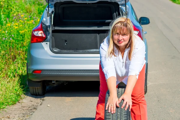 The female spare wheel rolls on the road — Stok fotoğraf