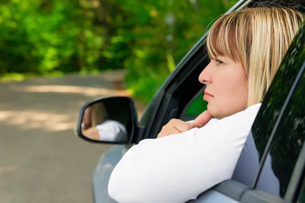 Nachdenkliche Autofahrerin 50 Jahre beim Blick aus dem Fenster — Stockfoto