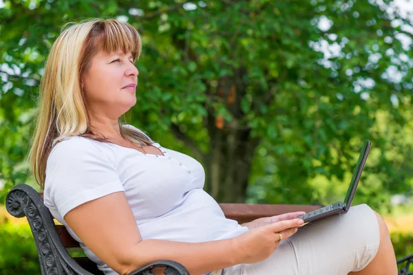 Female 50 years, relaxing in the park on fresh air — Stock Photo, Image