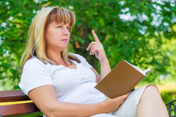 Mulher pensativa com um livro no parque — Fotografia de Stock