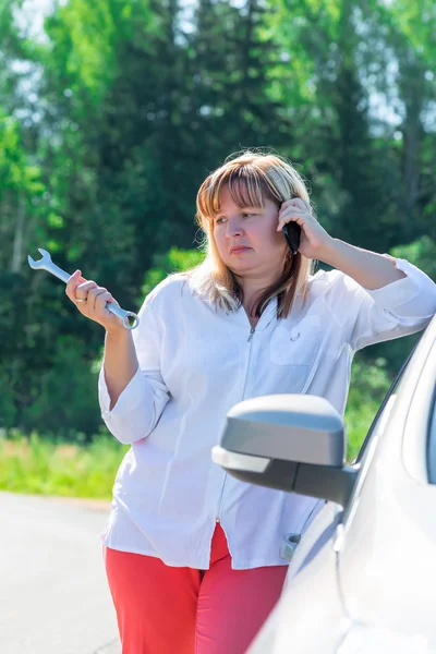 Retrato de uma mulher com uma chave perto do carro quebrado — Fotografia de Stock