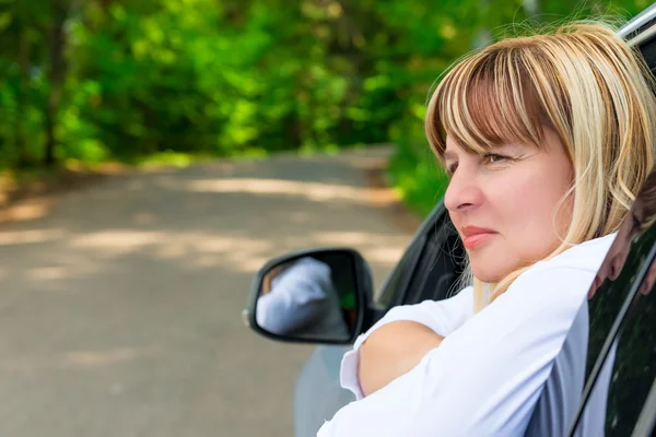 Portrait of a pensive female driver 50 years looking out the win — Stock Photo, Image
