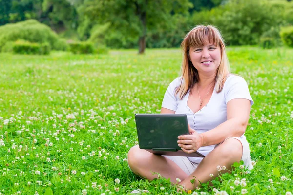 Gladlynt kvinna med en laptop på sommaren ängen — Stockfoto