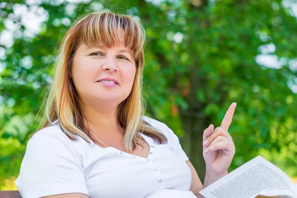 Joyful woman of 50 years on the bench with a book — Stock Photo, Image