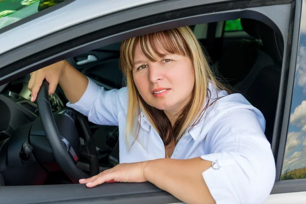 彼女の車のホイールの後ろに成熟した美しい女性の肖像画 — ストック写真