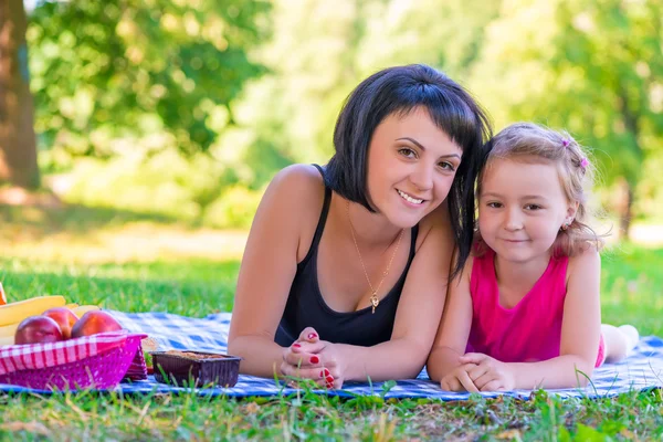 Portrét smějící se matka a její dcera na trávníku — Stock fotografie