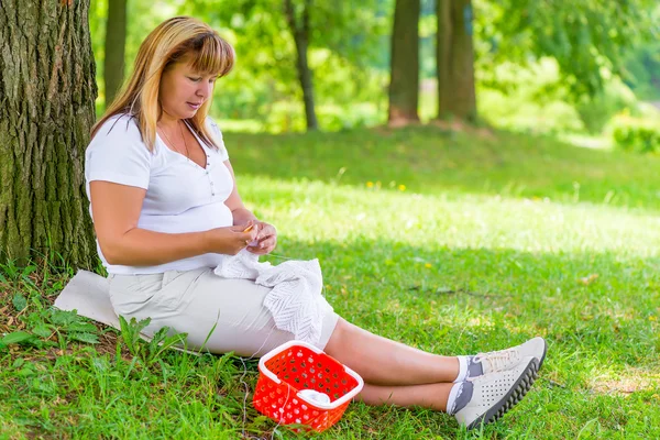 50-year-old woman knitting in the summer park — Stock Photo, Image