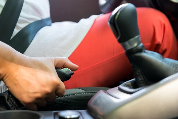 Woman's hand picks up the parking handbrake in a car — Stock Photo, Image