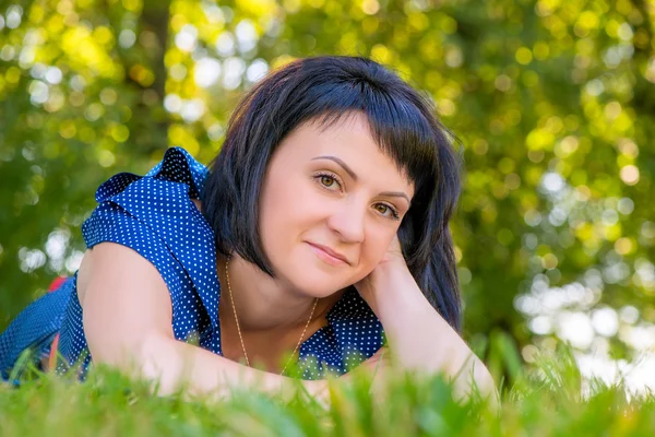 公園の緑の草の上に横たわる美しい若い女性 — ストック写真