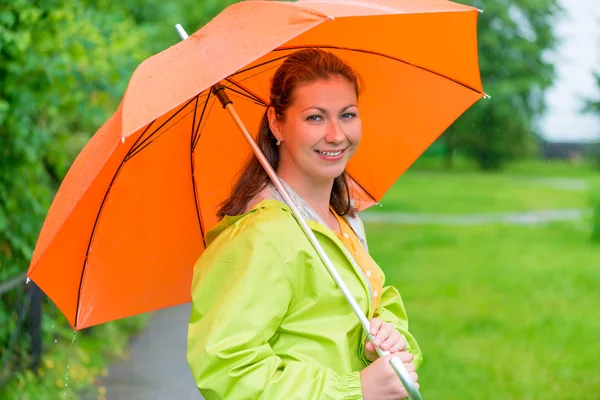 Fille souriante de 30 ans tenant un parapluie sous la pluie — Photo