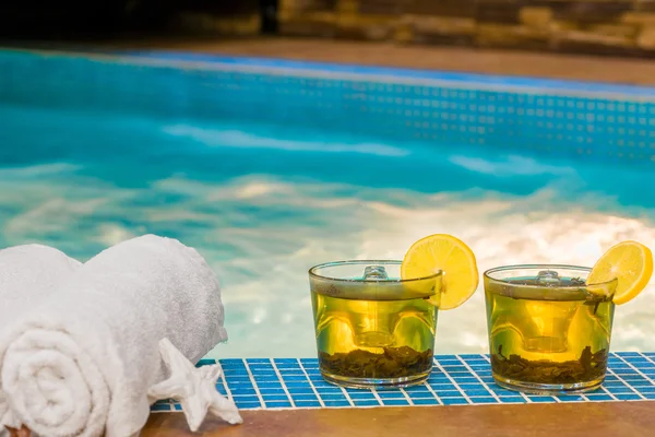Refreshing green tea and towels by the pool — Stock Photo, Image