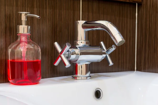 Shiny faucet and soap dispenser in the bathroom close up — Stock Photo, Image