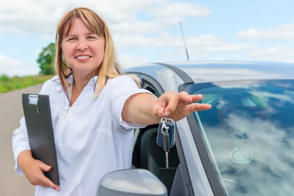 Portret van een vrouw in de buurt van de auto. sleutels in zijn hand in focus — Stockfoto