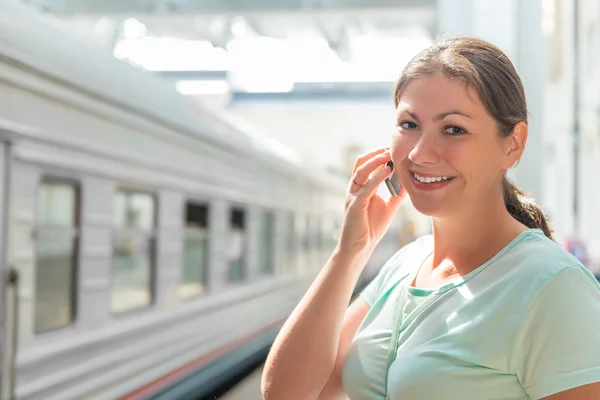 Šťastný bruneta s mobilním telefonem na stanici — Stock fotografie