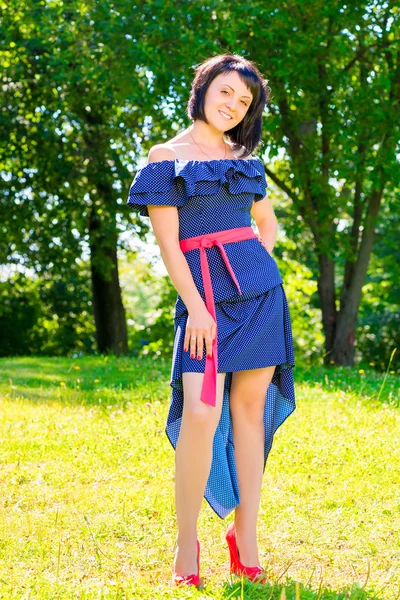 Szczupła ładna dziewczyna w sukience pozowanie na trawnik w parku — Zdjęcie stockowe