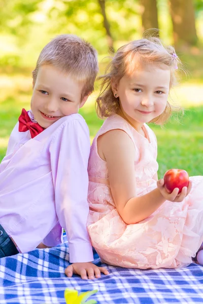 Meisje met perzik en een kleine man op de picknick — Stockfoto