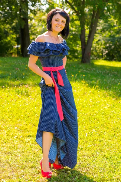 Mooi meisje in een blauwe lange jurk poseren in het park — Stockfoto