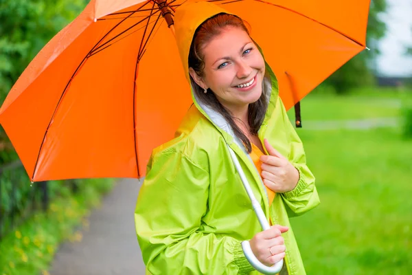 Brunette lachen onder een oranje paraplu-closeup Stockfoto